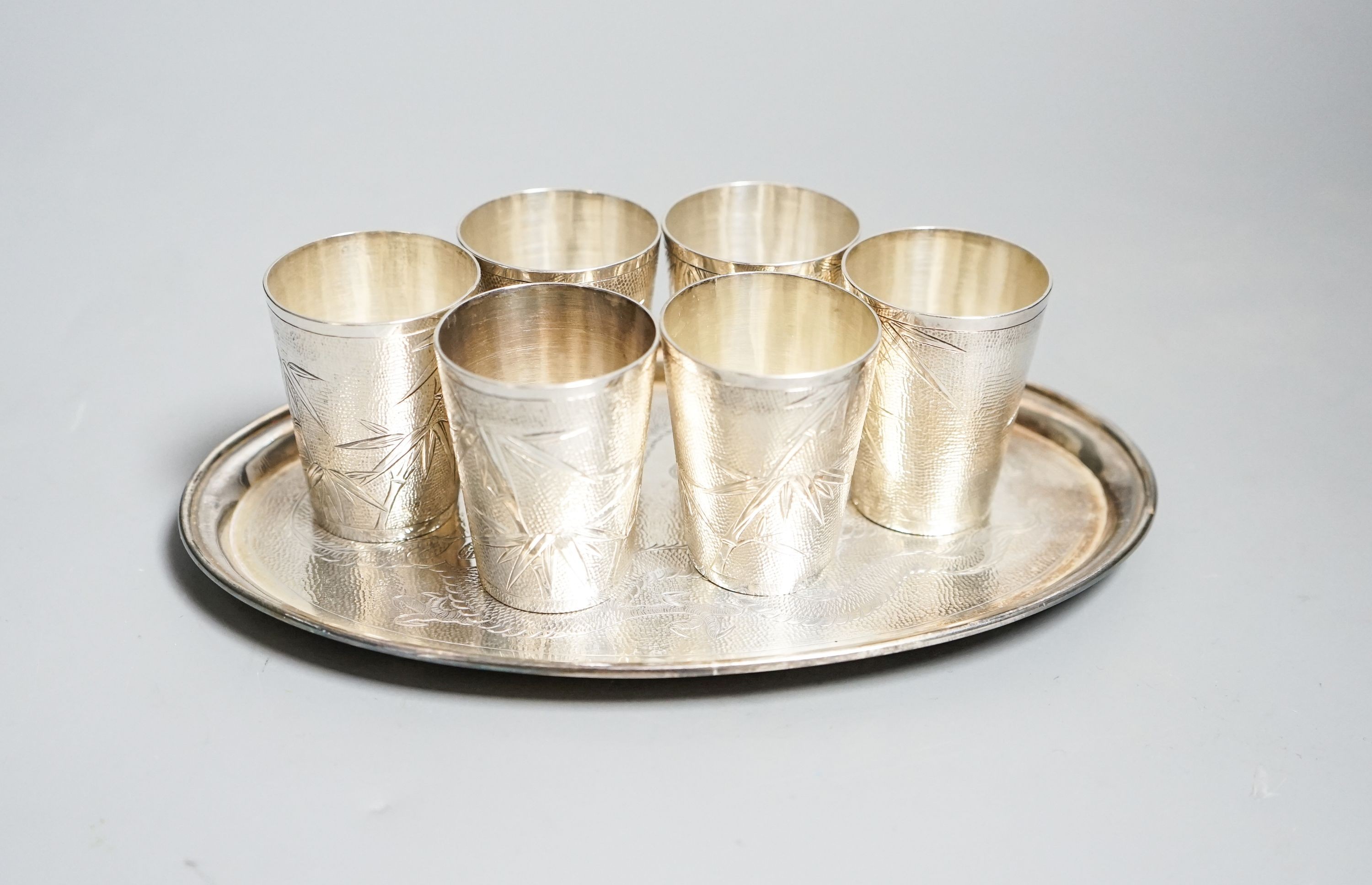 A set of six Chinese white metal tots by Tack Hing, 50mm and a small oval tray by Kingsburg, Hong Kong, 10.5oz.